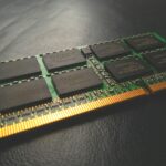 Stick of laptop memory on a black table, highlighting individual chip dies