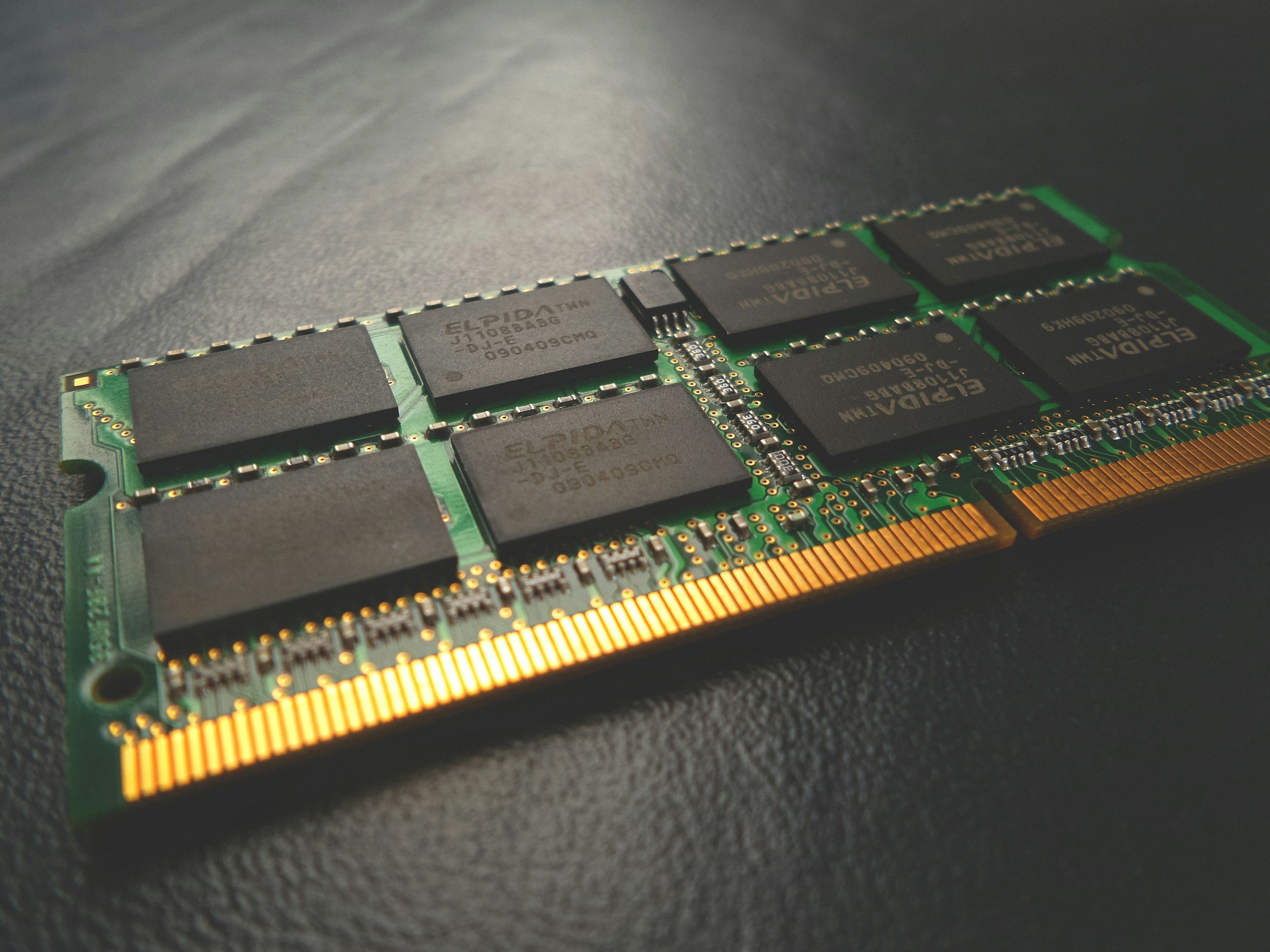 Stick of laptop memory on a black table, highlighting individual chip dies